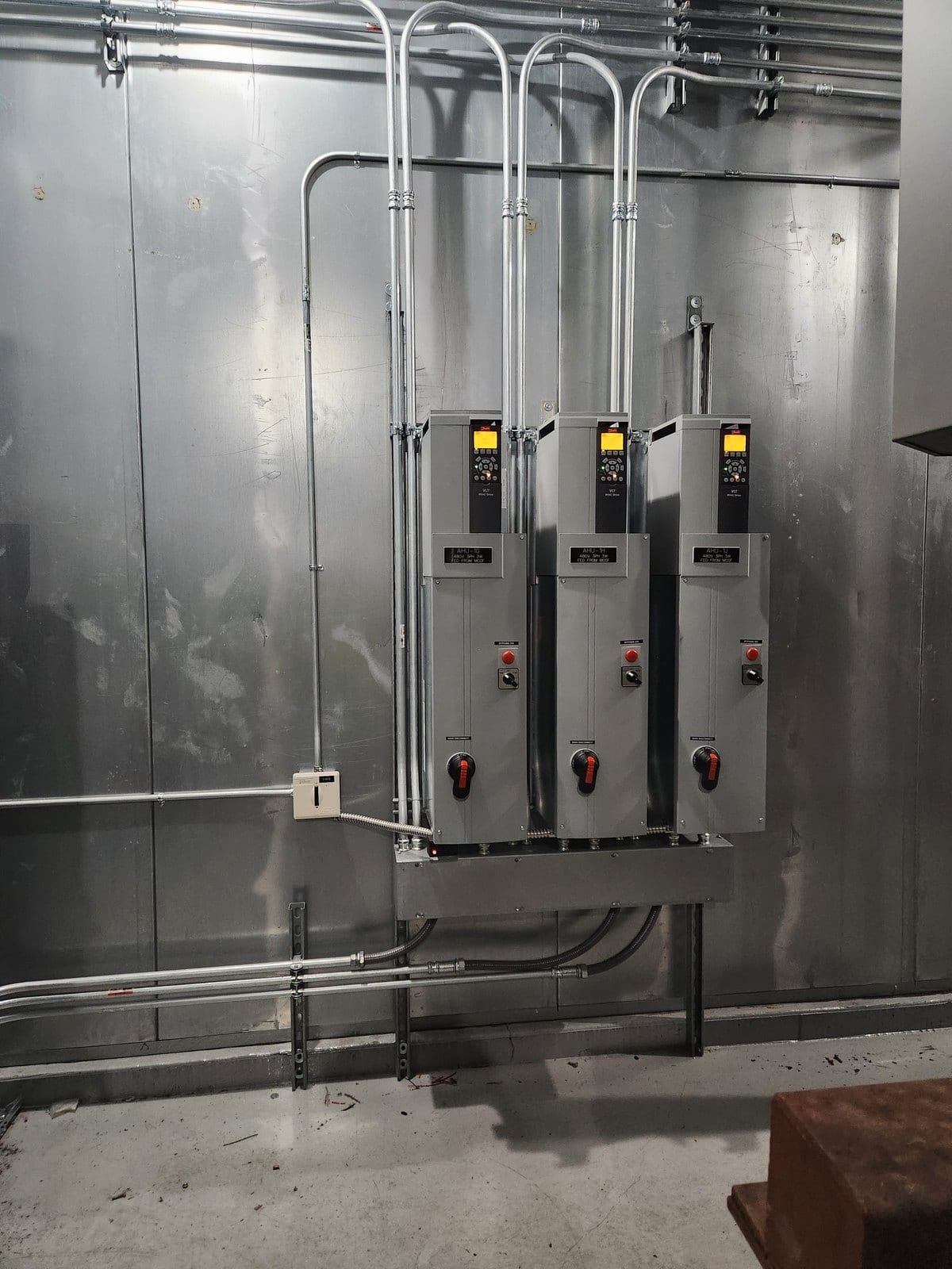 Three fused disconnect switches mounted on a metal wall with conduit drops