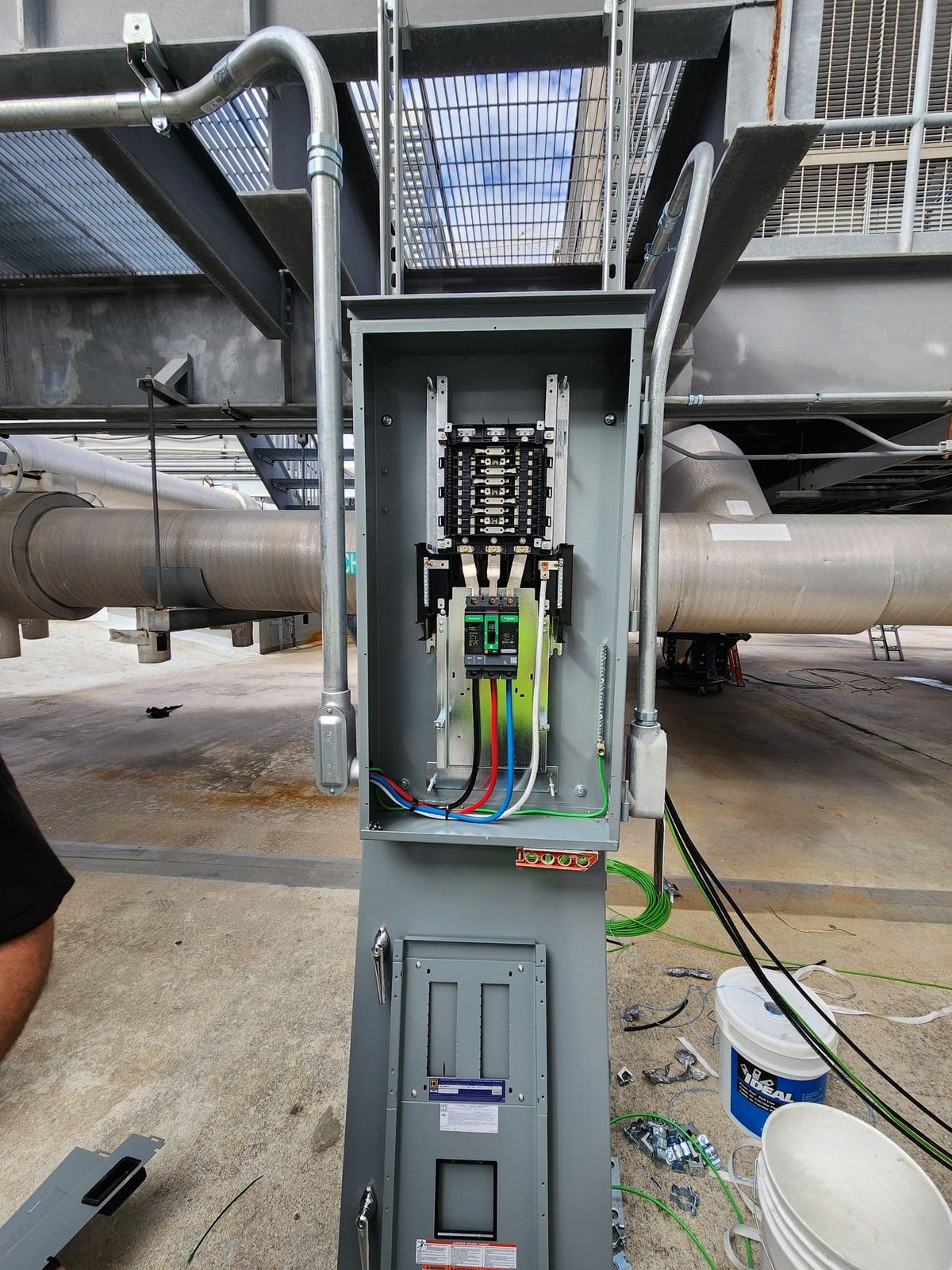 Pedestal-mounted service enclosure open, showing breaker and colour-coded conductors