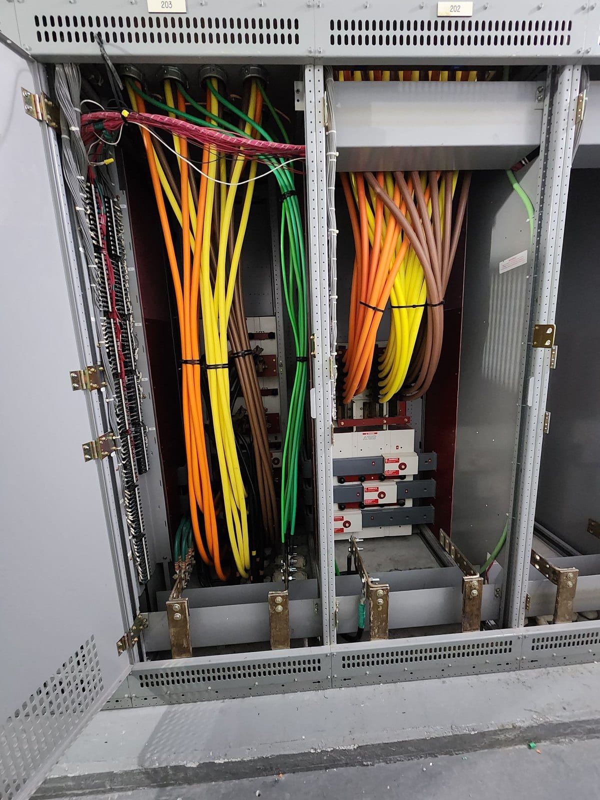 Open switchgear section with orange, yellow and green parallel feeder conductors bundled to the bus